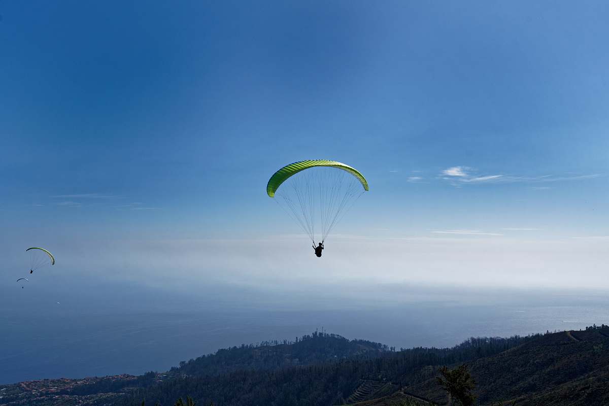 leisure activities person paragliding over mountain during daytime gliding